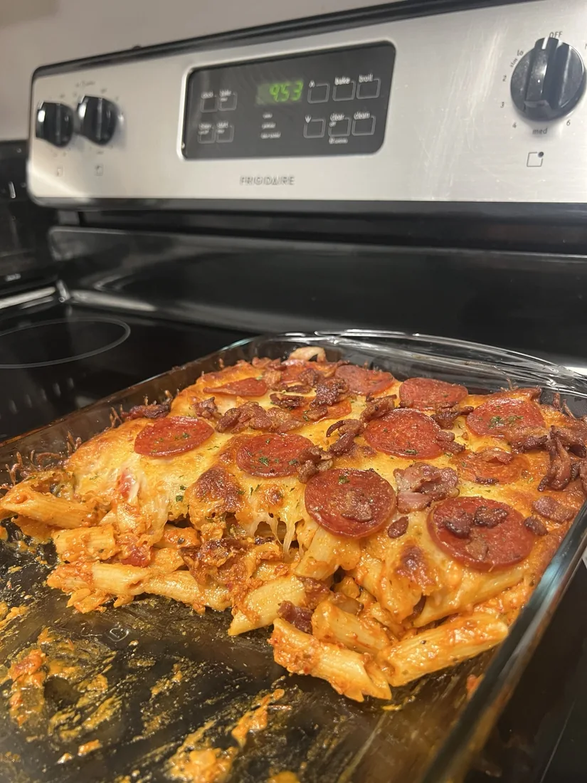 Homemade baked penne pasta with melted cheese, pepperoni and bacon