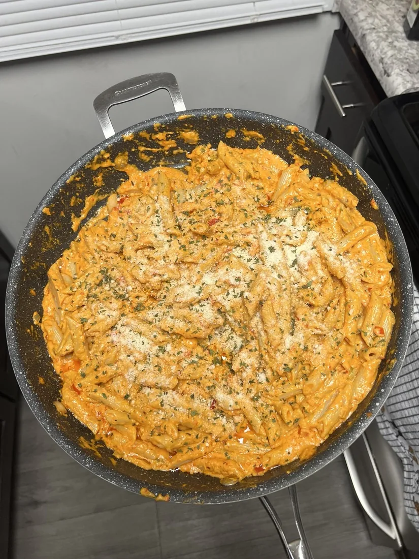 Orange creamy penne pasta topped with grated cheese and herbs